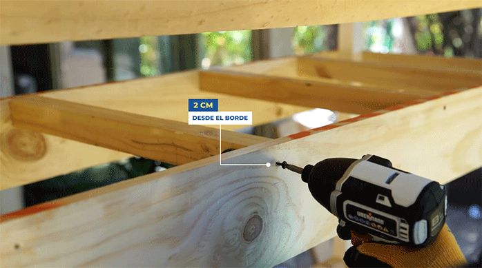 una persona fija los soportes para los maceteros en el interior de la estructura de la jardinera movible.