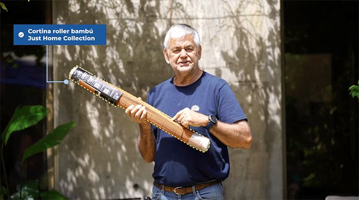 un hombre adulto mayor sostiene en sus manos una cortina roller de bambú Just Home Collection.