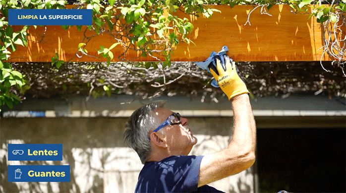 un hombre limpia una viga de madera con un paño.