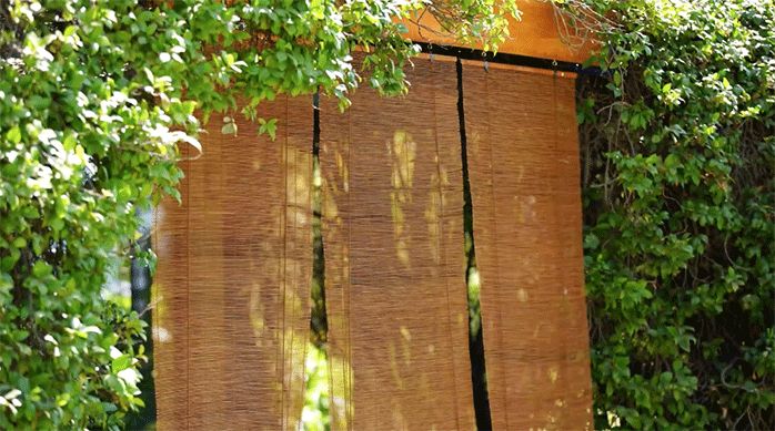 tres persianas de bambú recién instaladas una al lado de la otra en la viga de madera de una terraza.