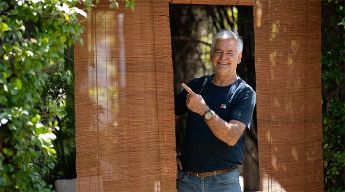 un hombre mostrando las persianas de bambú que acaba de instalar en la terraza de una casa.