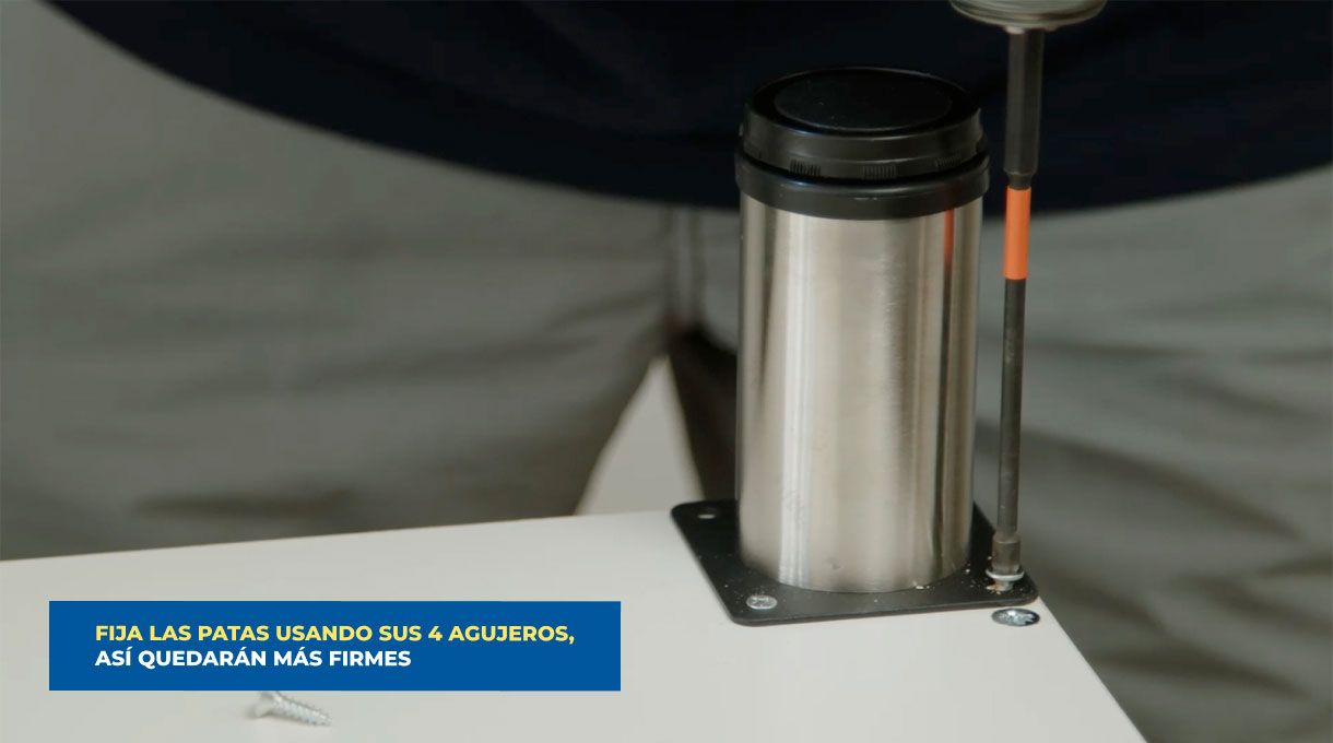 una persona fija las patas de un mueble de cocina que tiene lavaplatos y encimera.