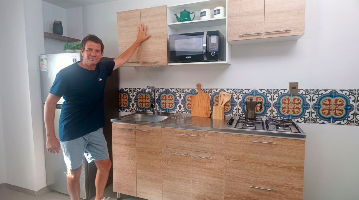 un hombre frente a un mueble de cocina recién armado, que cuenta con lavaplatos y encimera.