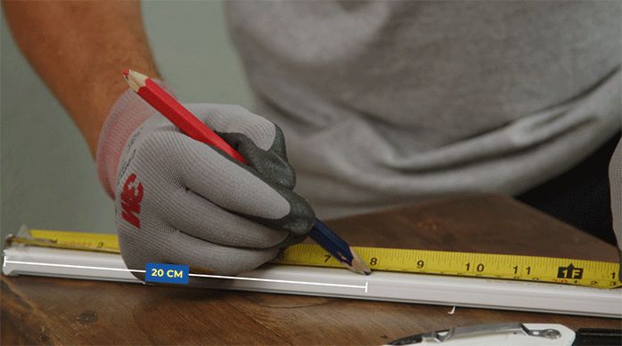una persona mide una canaleta eléctrica con una huincha de medir.