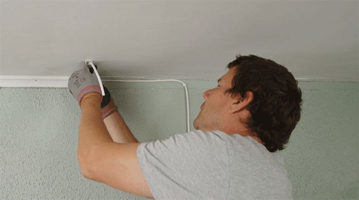 una persona instala un cable eléctrico en el cielo de una habitación.