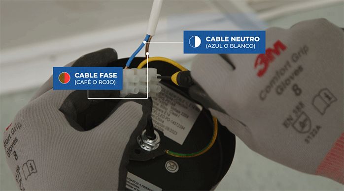 una persona con guantes de seguridad conecta una lámpara.