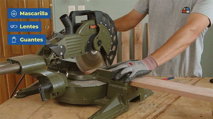un hombre con guantes de seguridad usa una sierra ingleteadora para cortar los trozos de roble vaporizado para decorar un muro con madera.