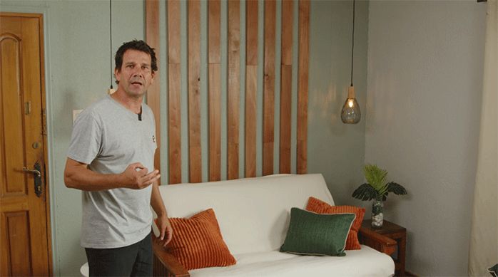 un hombre frente a un muro de living que acaba de decorar con trozos de roble vaporizado.