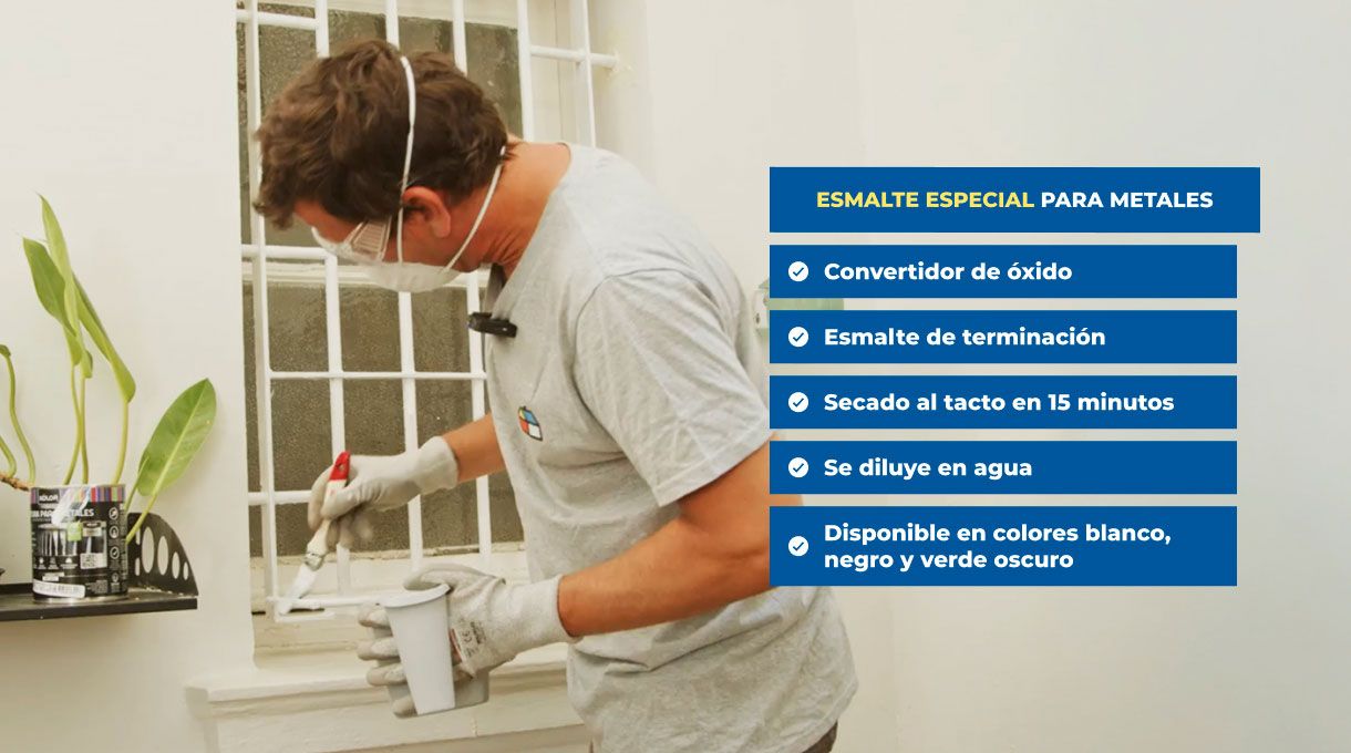 un hombre con elementos de seguridad aplica esmalte especial para metales en la reja metálica de una ventana.