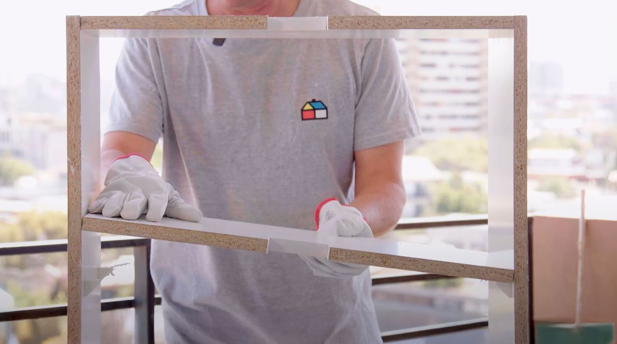una persona instala la repisa interior del mueble organizador de cables.