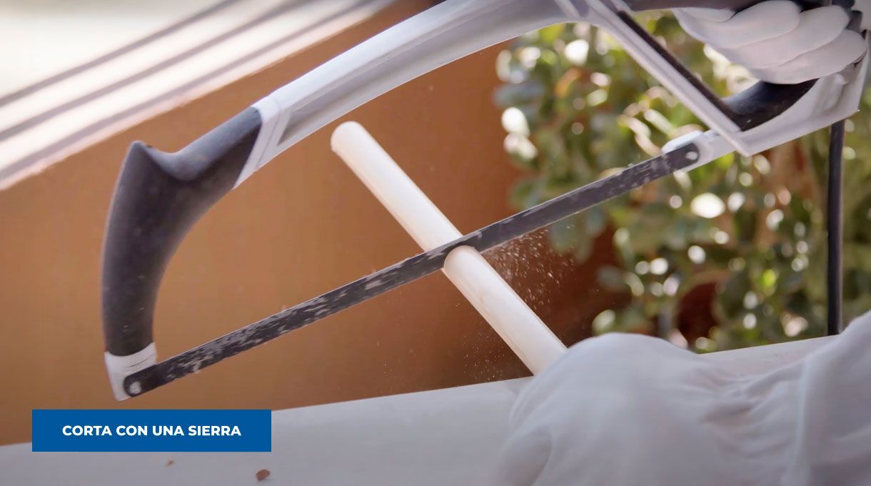 una persona corta una barra de madera con una sierra manual.