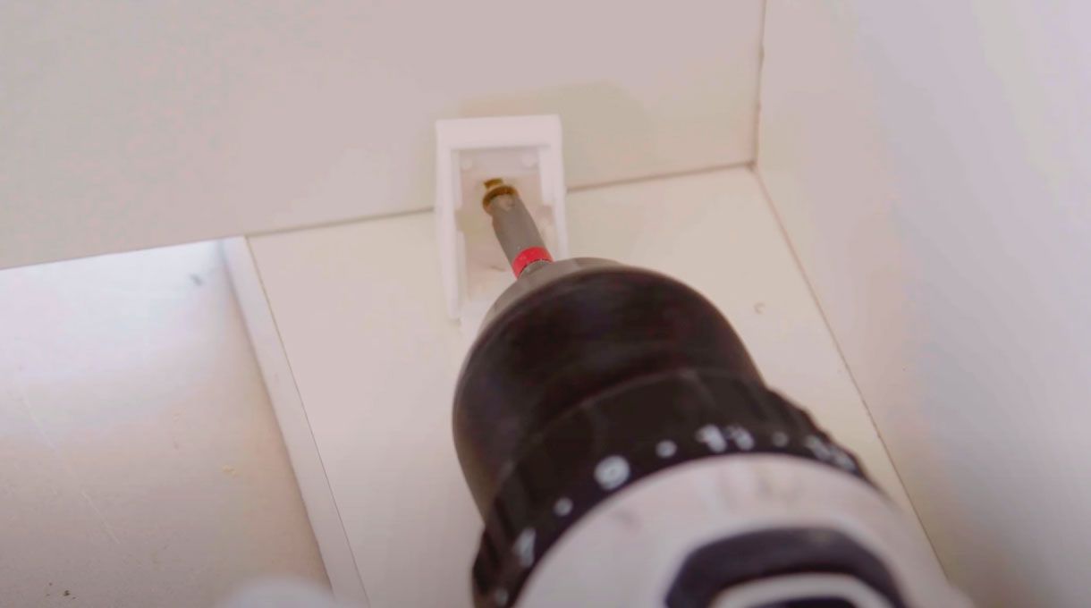 una persona fija el dintel del mueble organizador de cables usando unas escuadras plásticas.
