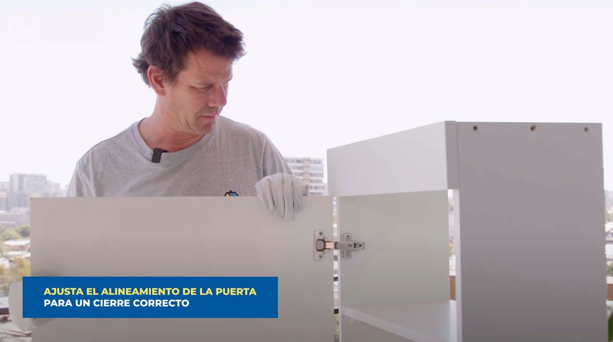 un hombre presenta la puerta en el mueble organizador de cables para fijar su bisagra y alinearla bien.