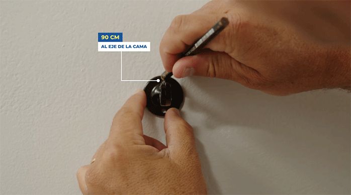 una persona marca el lugar de las fijaciones de un soporte para barra de cortina.