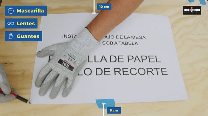 una persona con guantes de seguridad dibuja el contorno de una plantilla en un trozo de madera.