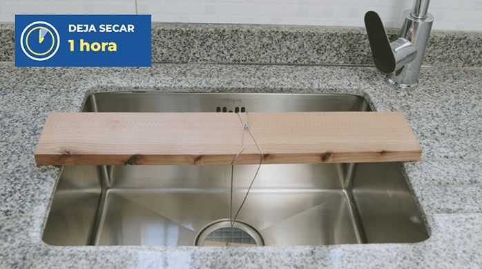 un lavaplatos bajo cubierta recién pegado en la cubierta de granito, con una madera puesta encima para sostenerlo en su posición.