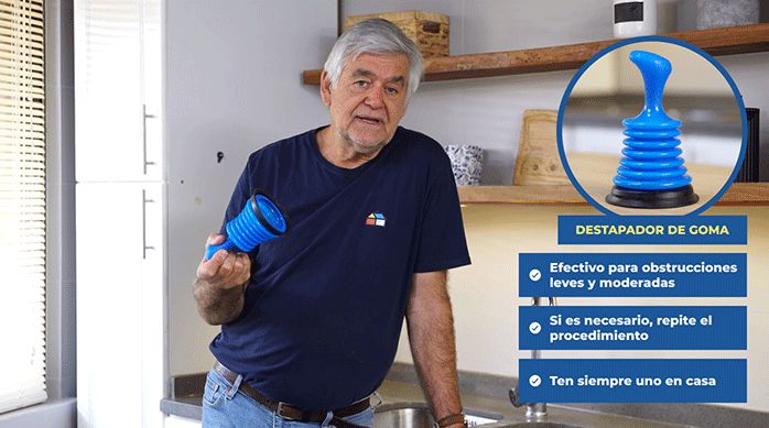 un hombre mayor sostiene un sopapo o destapador manual de goma azul en una cocina.