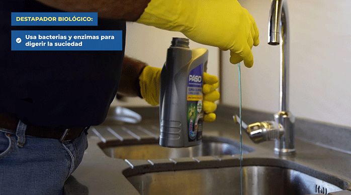 una persona vierte un poco de destapador biológico en el desagüe de un lavaplatos para destaparlo.