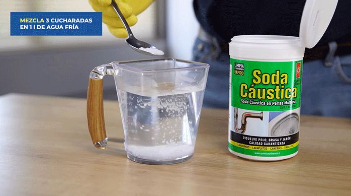 una persona disuelve un poco de soda cáustica en agua fría.