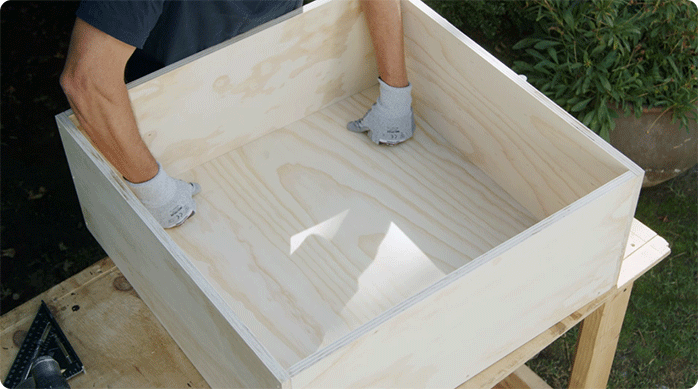 una persona pone la base de la mesa de centro dentro del cajón estructural del mueble.