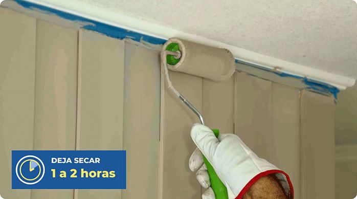 una persona pinta el muro de un dormitorio que tiene listones de MDF como revestimiento.