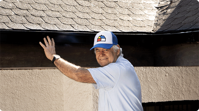 un hombre mayor frente a las canaletas de una casa que acaba de pintar con pintura para metales Kölor.