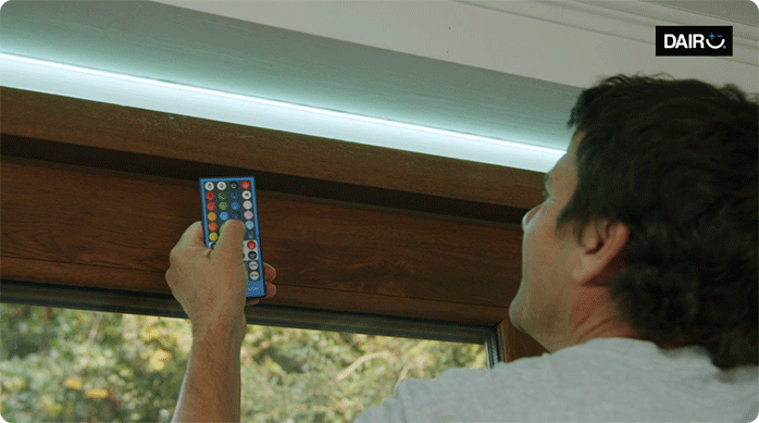 una persona usa el control remoto de la cinta de luces led para cambiar el color de las luces.