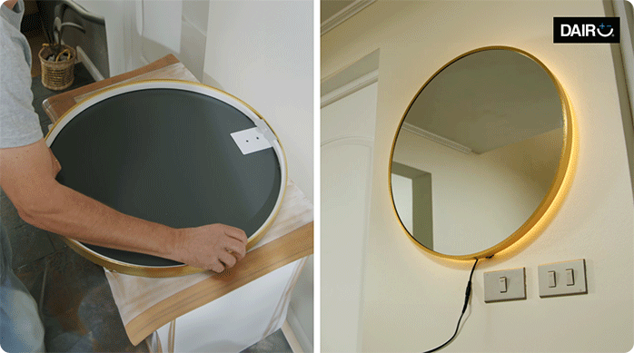 un hombre posiciona el perfil de silicona con luces led en la parte posterior de un espejo circular y luego lo cuelga en un muro.