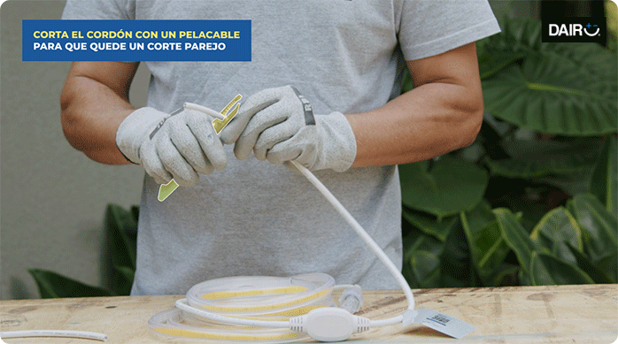 un hombre corta el cordón de la tira de luces led con un pelacables para dejar al descubierto los cables interiores.