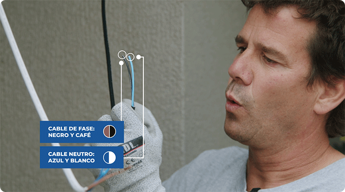 un hombre muestra los cables fase y neutro de un cordón eléctrico.