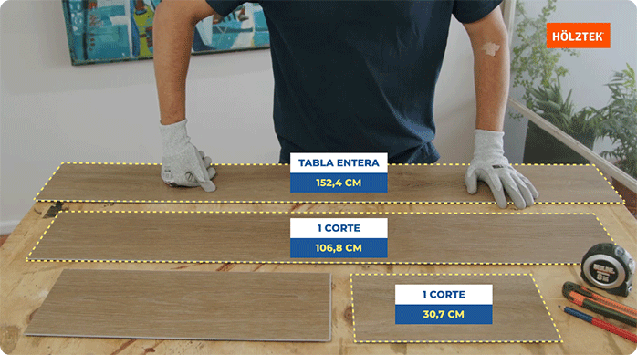 un hombre apoyado en un mesón en que tiene varios cortes de piso vinílico imitación madera.
