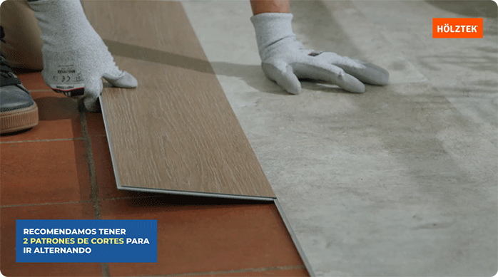 una persona encaja una palmeta de piso vinílico con textura de madera en un piso vinílico con textura de piedra.