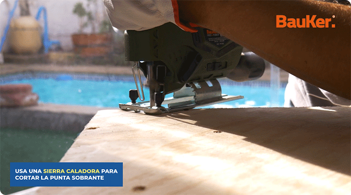 una persona corta la punta del mueble esquinero con una sierra caladora.