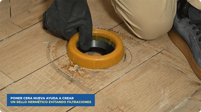 una persona pone el nuevo sello de cera en el desagüe.
