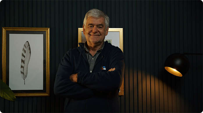 un hombre adulto mayor con polerón azul frente a un muro que recién acaba de remodelar usando paneles ranurados, WPC o wall panel.
