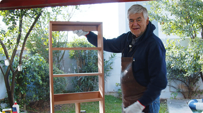 un hombre presenta el soporte superior del mueble estante para baño pequeño.