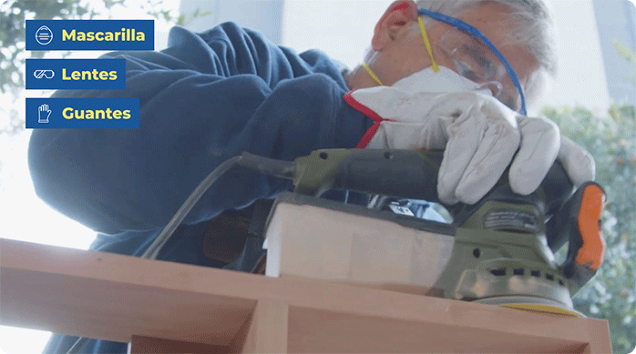 un hombre con elementos de seguridad suaviza la superficie del mueble estante con una lijadora roto orbital.