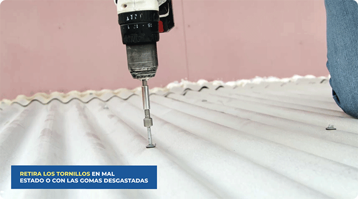 una persona usa un desatornillador inalámbrico para retirar los tornillos del techo de zinc que están en mal estado.