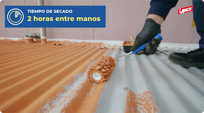 una persona aplica la pintura anticorrosiva en el techo de zinc usando un rodillo.