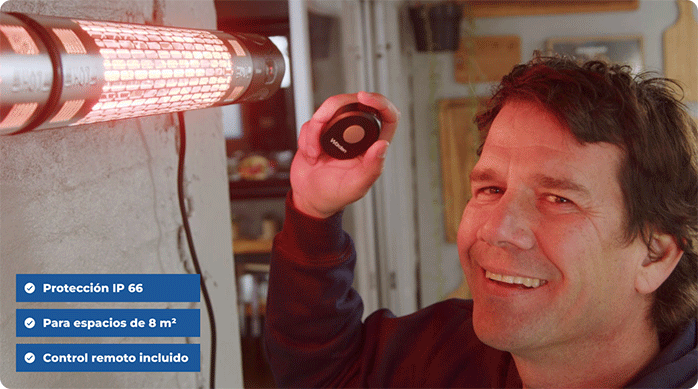 un hombre frente al calefactor eléctrico de exterior recién instalado, encendiéndolo con el control remoto.
