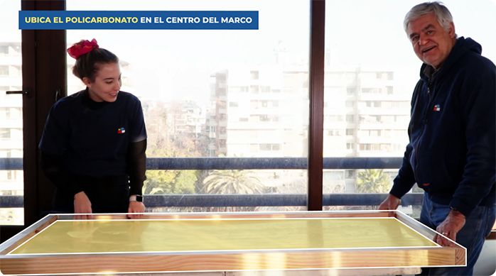 una mujer y un hombre presentan una plancha de policarbonato en un marco hecho de pino.