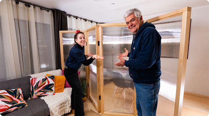 una mujer y un hombre en un living presentan muy felices el biombo de policarbonato que acaban de construir.