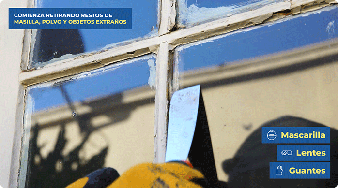 una persona usa una espátula para sacar los restos de masilla de una ventana de madera.