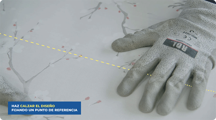 una persona hace coincidir el diseño del papel mural entre dos pliegos.