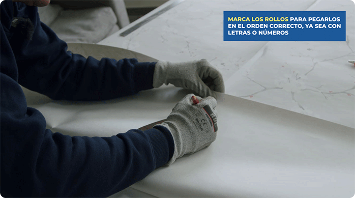 una persona marca los rollos de papel mural por su reverso.