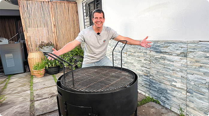 un hombre feliz muestra una parrilla que acaba de recuperar eliminando el óxido y aplicando spray negro.