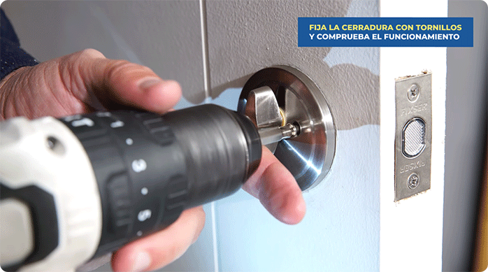 una persona atornilla la parte con pestillo de un cerrojo simple fixser en la puerta de una bodega de departamento.