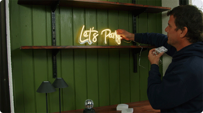 un hombre pone unas luces led decorativas en su nuevo mini bar de balcón.