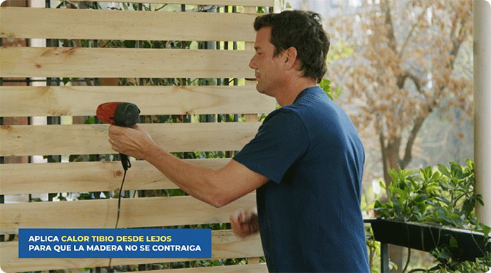 un hombre usa un secador de pelo para secar la superficie de la madera que acaba de limpiar con la solución de agua y cloro.