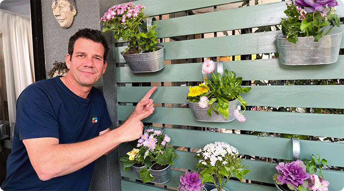 un hombre feliz muestra cómo quedó el quiebra vista con jardineras que acaba de reparar, eliminando los hongos de la madera.